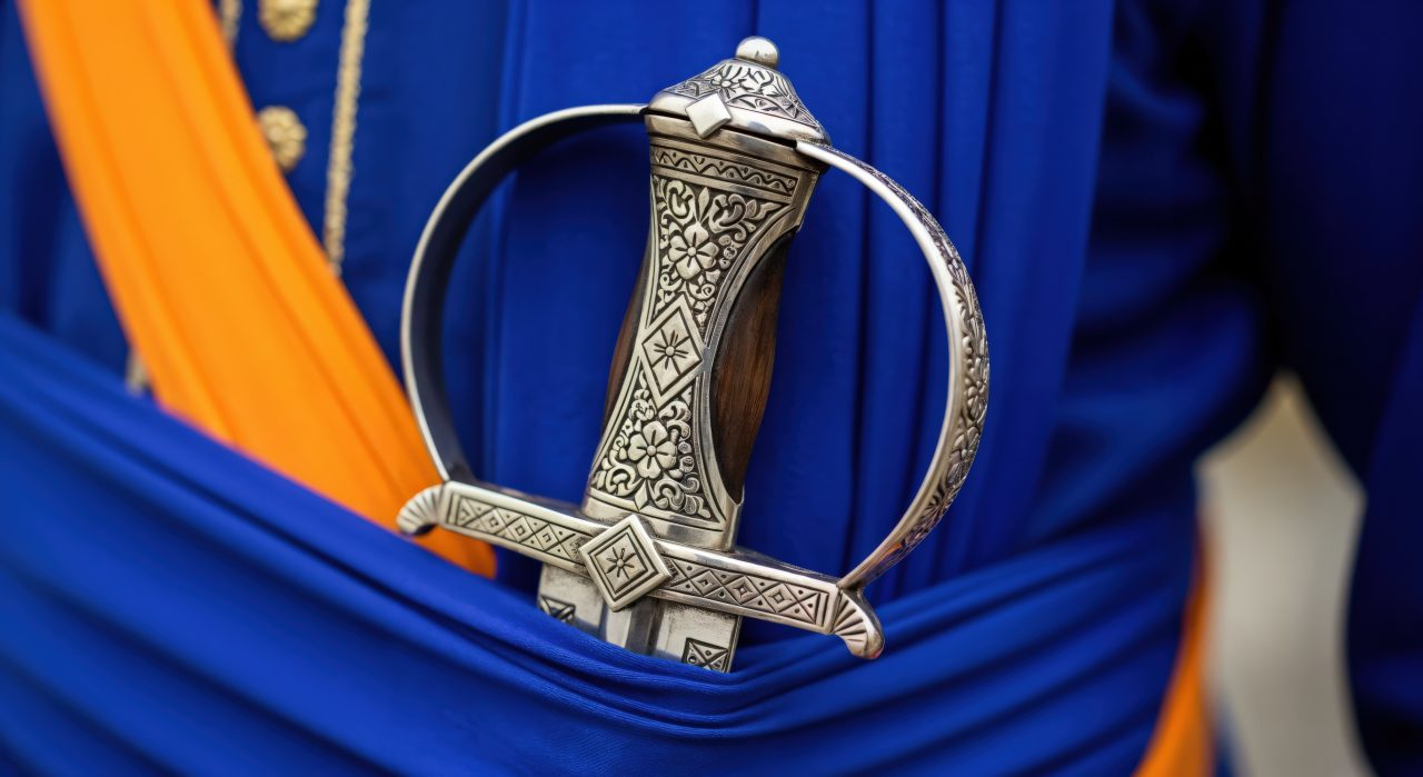 En kirpan, en dolk med utskjæringer stikker opp av linningen på en bukse.