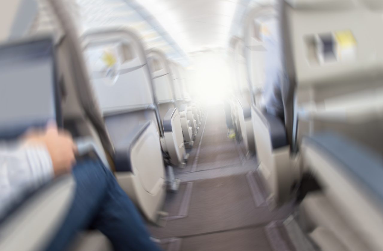 Fly rister under turbulens som flyr med lufthull. Sløret bilde av et kommersielt fly som beveger seg raskt nedover.